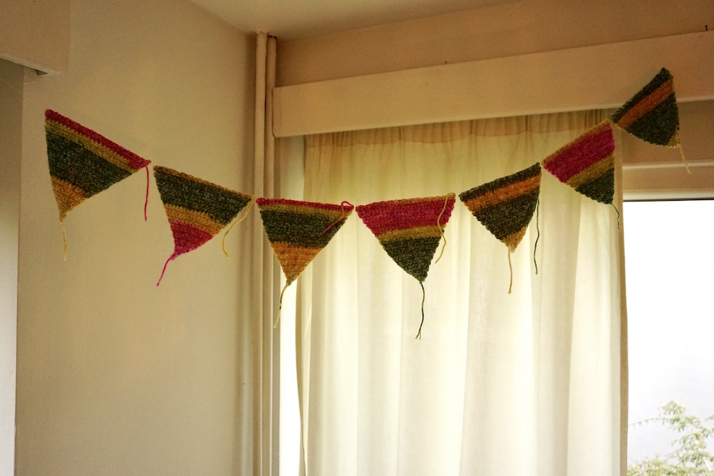 Gehaakte slinger bestaande uit kleurrijke driehoekjes, opgehangen als decoratie