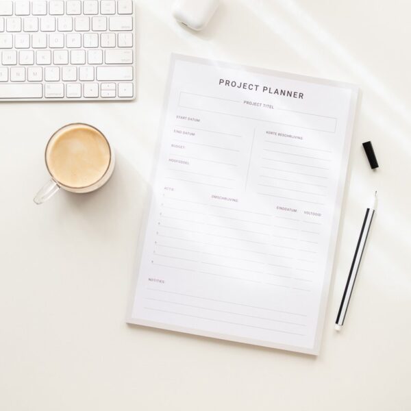 Projectplanner voor haakprojecten op een creatief bureau Projectplanner voor haakprojecten liggend op een wit bureau met een toetsenbord, muziekoortjes, een pen en een koffietje – klaar voor creatieve plannen
