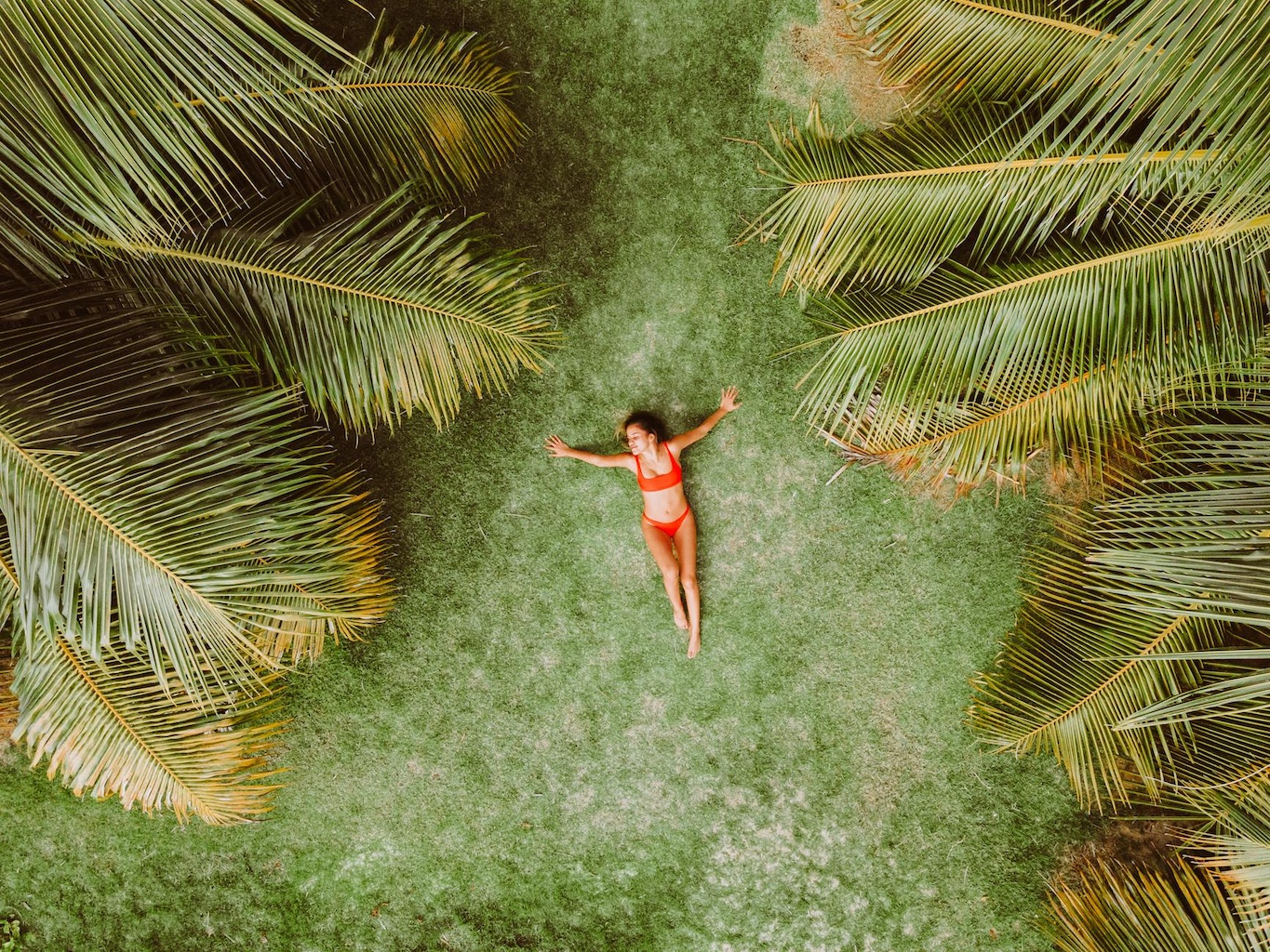 Vrouw in bikini ontspant in een rustige, groene omgeving met grote palmbladeren – symbool voor rust en mindfulness